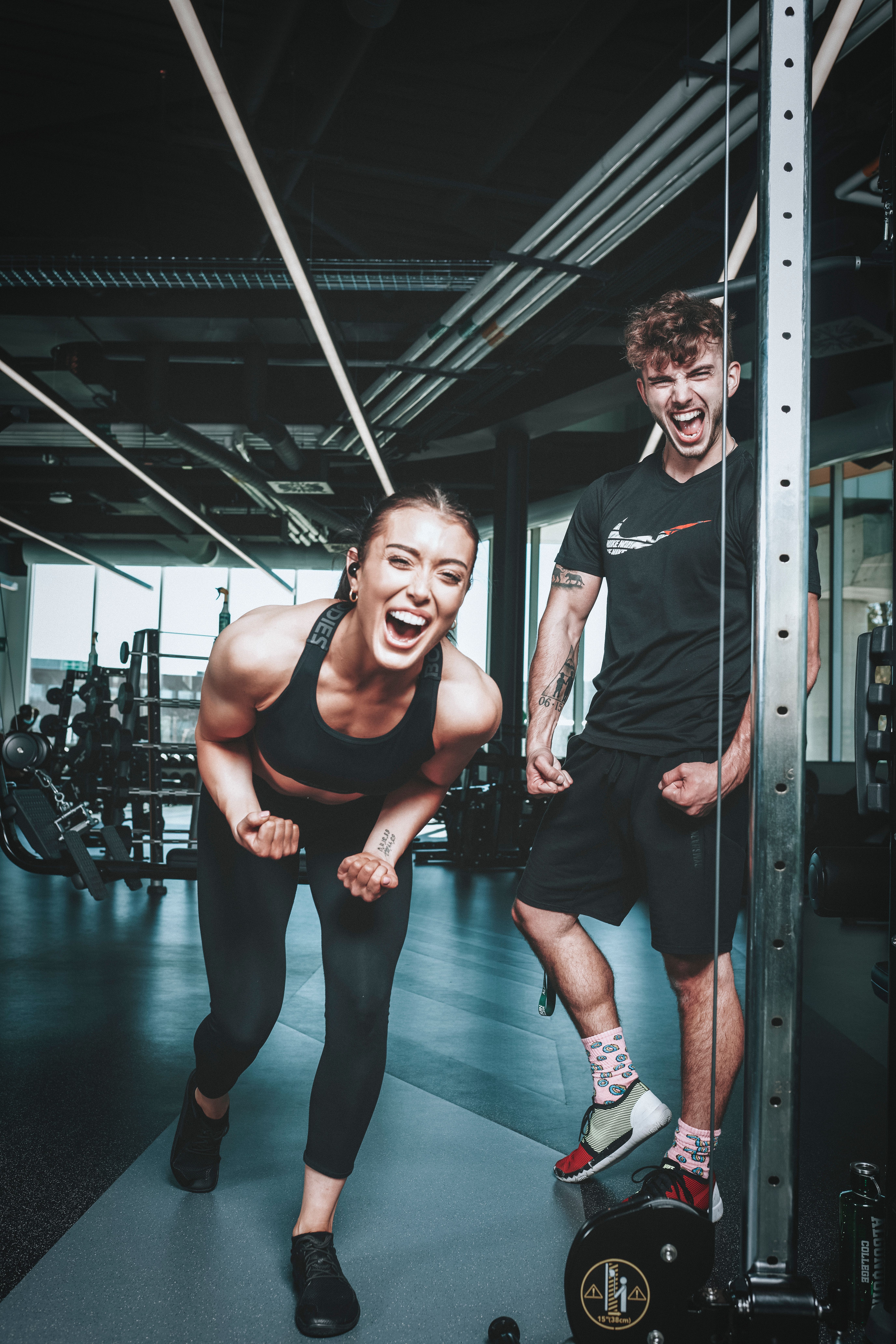 Homem e mulher comemorando dentro da academia, sorrindo e vibrando