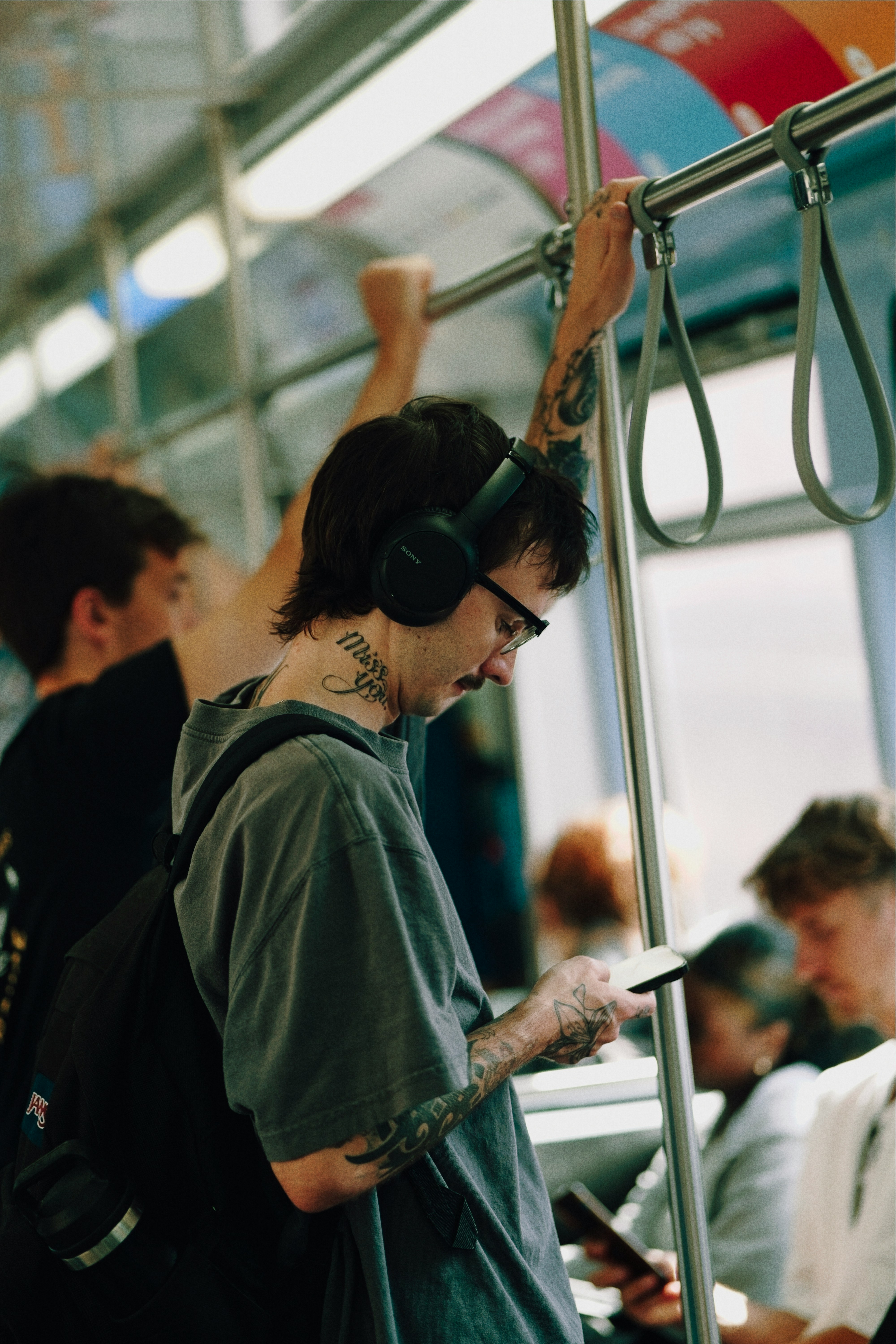Homem em pé no metrô, olhando para o celular com o pescoço flexionado para baixo