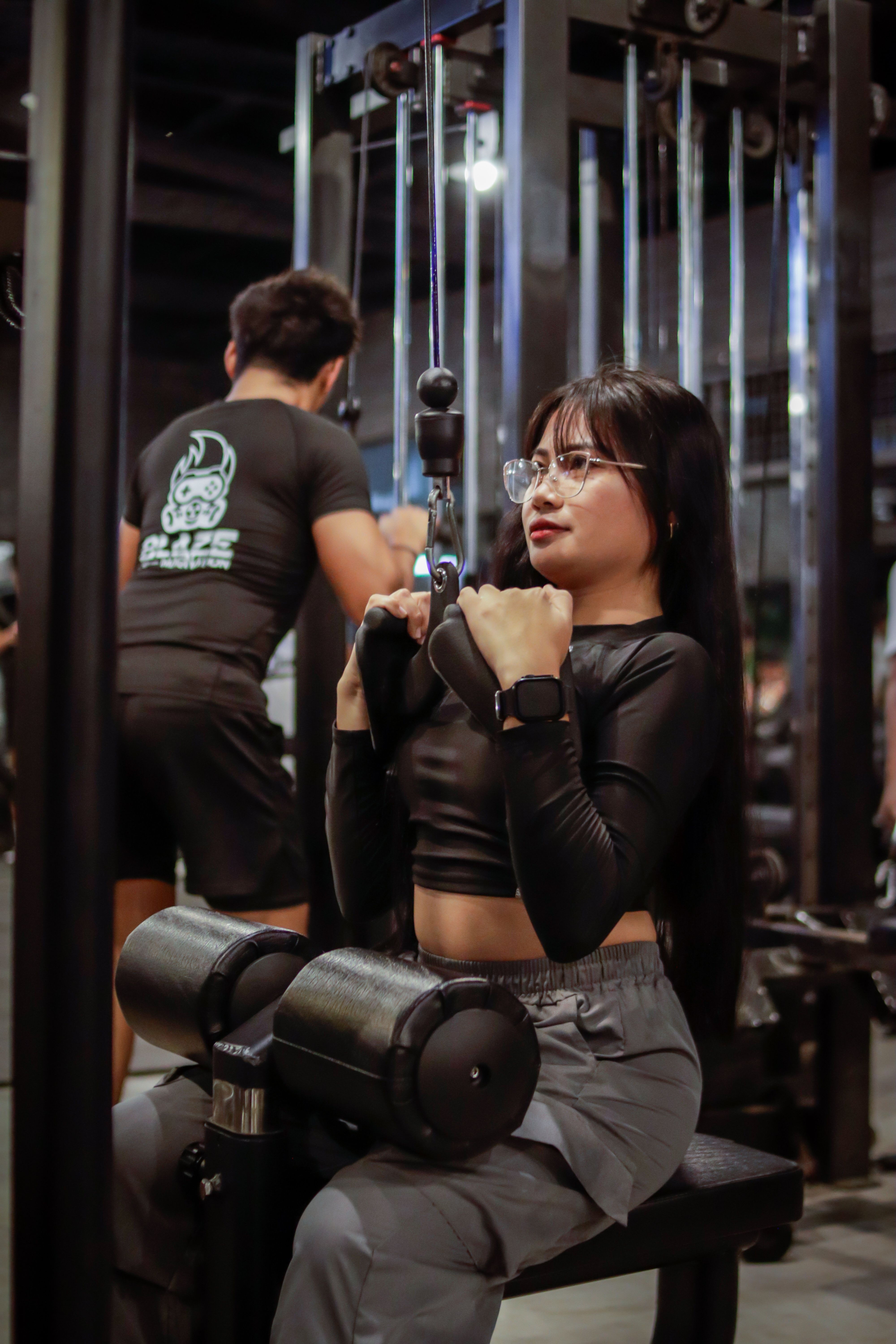 Mulher fazendo um exercício de puxada na polia alta em uma academia